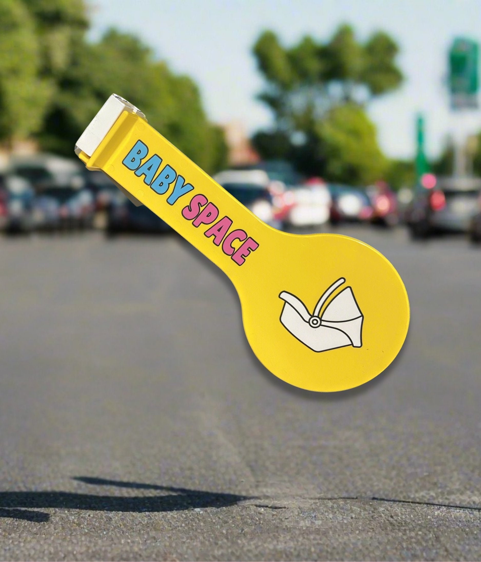 A floating bright yellow Baby Space sign with a parking lot in the background.