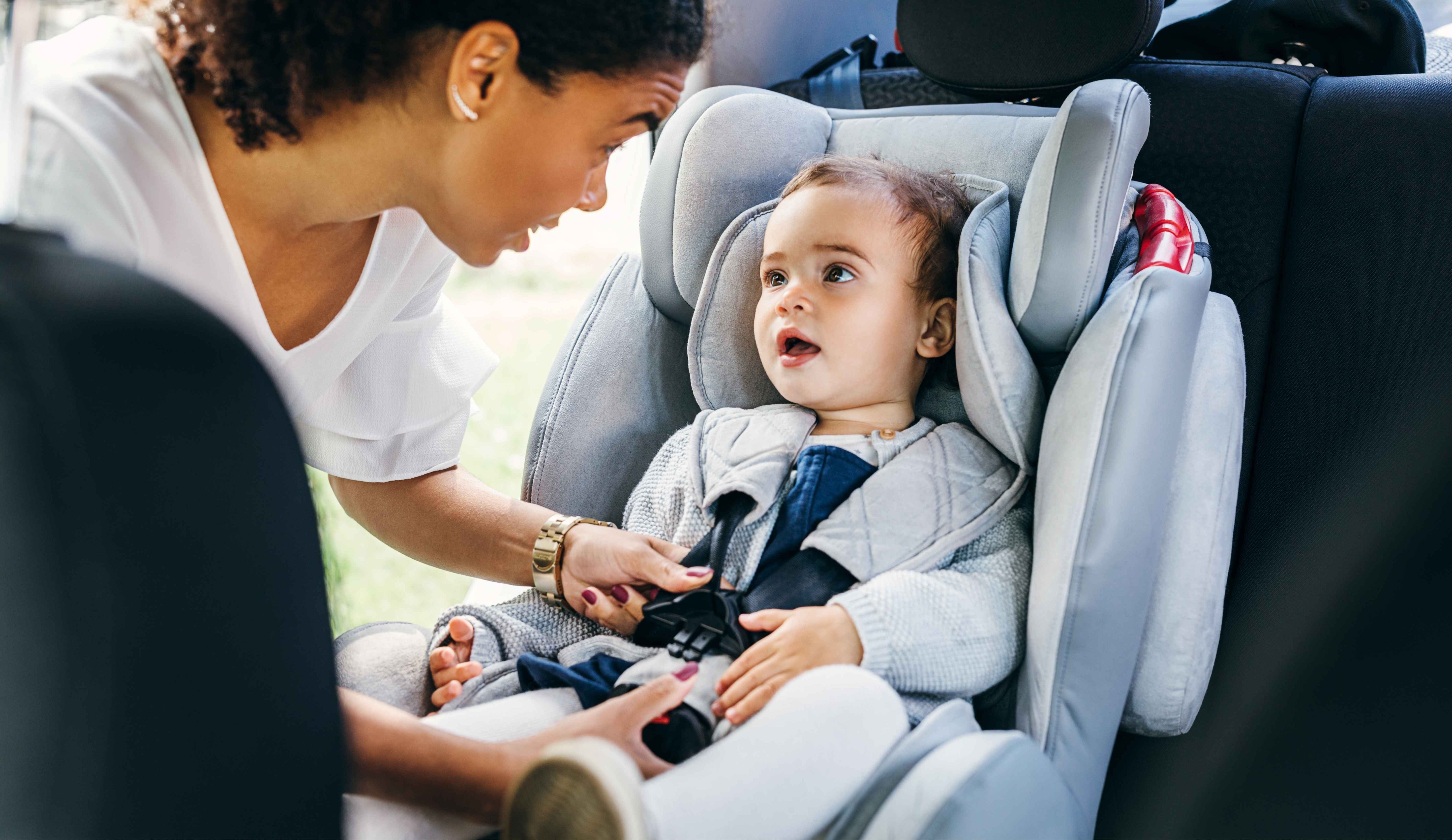 Mother securing her baby in the infant car seat.