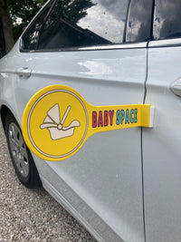 The Baby Space sign attached to a white car, a must-have for new parents who need safe space to load their baby.